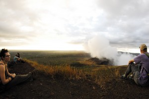 Smoke rises from the volcano while the sun sets.